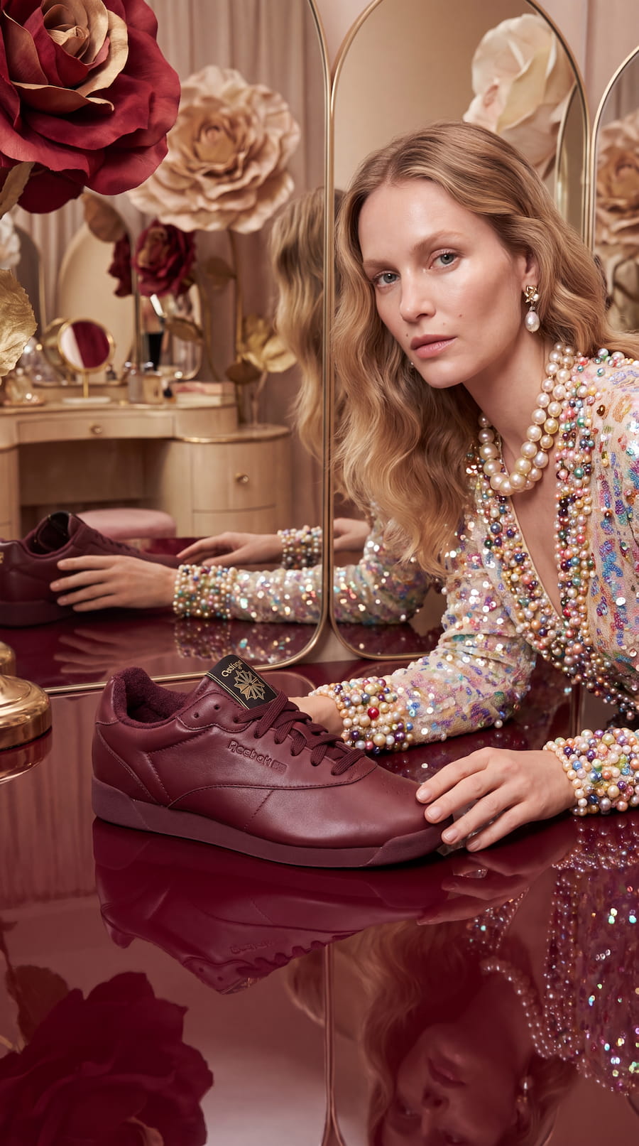 AI-generated editorial fashion image of a model in a pearl-embellished outfit presenting a burgundy Reebok Freestyle Lo sneaker.